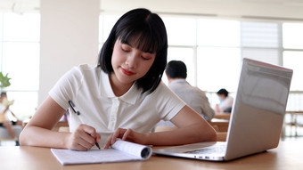 图书馆看书的女大学生学习阅读书写作业