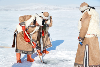 寒冷的冬季在冰冻的湖面上凿冰捕鱼的人们