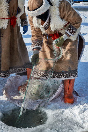 寒冷的冬季在冰冻的湖面上凿冰捕鱼的人们