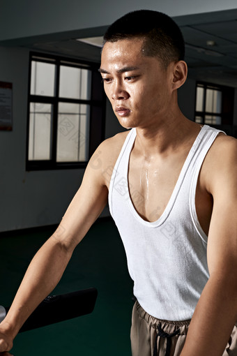 在室内用<strong>跑步机</strong>进行锻炼的亚洲健身男士形象