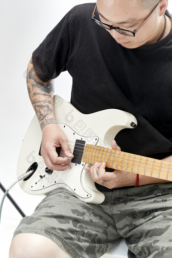 示范演奏摇滚电吉他的亚洲男性乐手人像局部特写