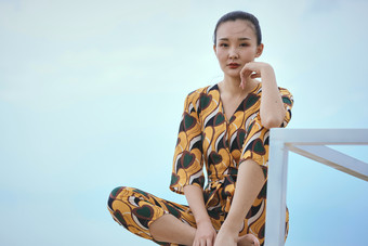 悠闲的坐在美丽湖岸码头的亚洲年轻女性人像