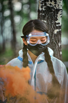 手执彩烟身穿防护服装的女性医疗人员