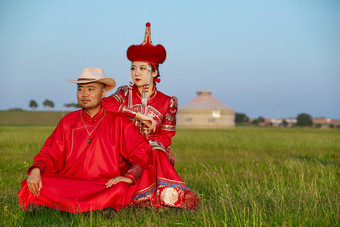 草原上蒙古包前穿蒙古族传统服饰的年轻夫妻