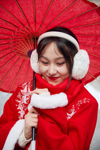 雪后在老城古巷穿着喜庆服饰的亚洲少女