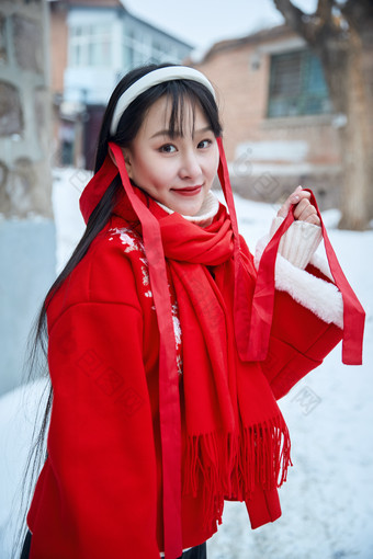 雪后在老城古巷穿着喜庆服饰的亚洲少女