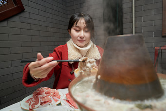 在饭店吃传统铜锅涮肉的亚洲少女