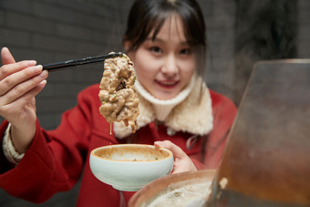 在饭店吃传统铜锅涮肉的亚洲少女