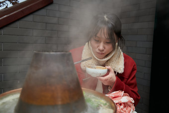 在饭店吃传统铜锅涮肉的亚洲少女