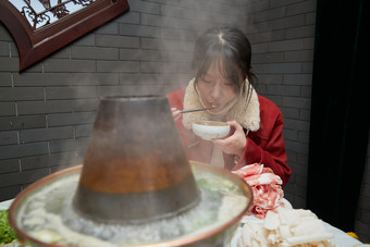 在饭店吃传统铜锅涮肉的亚洲少女