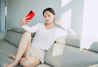 在沙发床上玩手机的年轻亚洲女性