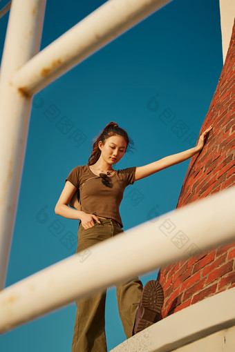 盛夏夕阳晚霞湖边码头灯塔上的少女