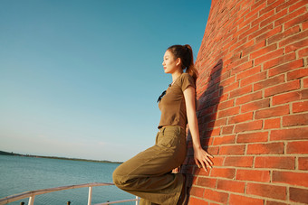 盛夏夕阳晚霞湖边码头灯塔上的少女