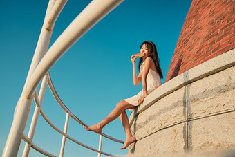 <strong>盛夏</strong>夕阳湖边码头灯塔上吃西瓜的少女