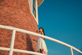 盛夏夕阳湖边码头灯塔上吃西瓜的少女