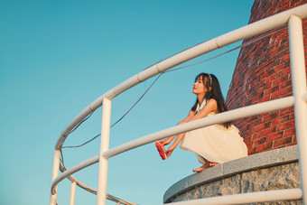 盛夏夕阳湖边码头灯塔上吃西瓜的少女