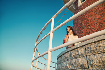 盛夏夕阳湖边码头灯塔上吃西瓜的少女