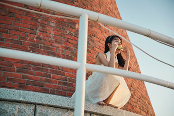 盛夏夕阳湖边码头灯塔上吃西瓜的少女