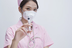 穿护士服戴听诊器口罩手执针筒的年轻女护士