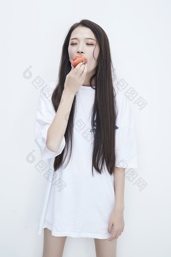 吃番茄的身穿白色长T血衬衫的长发少女人像