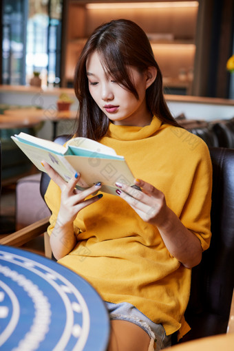 在图书咖啡馆阅读书籍的少女