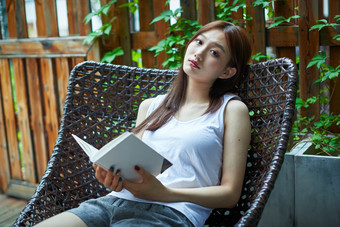 院子里坐在长椅上阅读书籍的亚洲长发少女