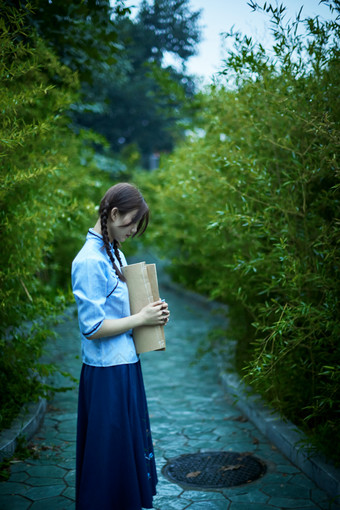 细雨中庭院里竹林前怀抱古书籍的<strong>民国风</strong>少女