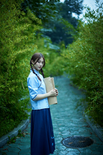 细雨中庭院里竹林前怀抱古书籍的民国风少女