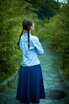 细雨中庭院里竹林前怀抱古书籍的民国风少女