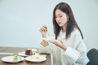 在烘焙店吃蛋糕喝饮料的可爱亚洲少女