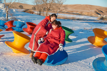 在冰天雪地玩耍雪上娱乐载具车辆的闺蜜少女