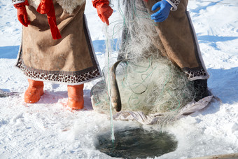 寒冷的冬季在冰冻的湖面上凿冰捕鱼