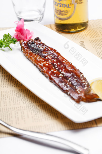 长方形瓷盘装的日式烤鳗鱼摆放在英文包装纸上