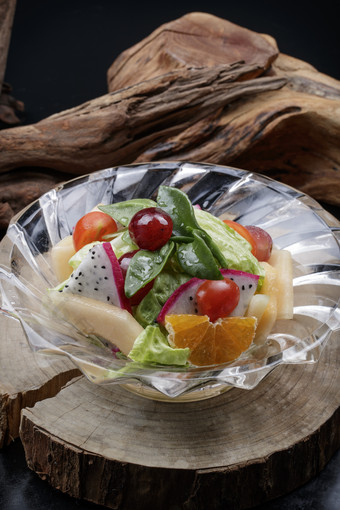 花纹玻璃碗装的<strong>果蔬</strong>拌菜摆放在樟木砧板上