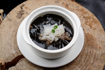 白色汤盅装的银耳龟苓膏摆放在樟木砧板上