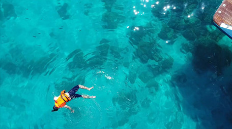 高空航拍在果冻色海洋里一个人浮潜寻找鱼