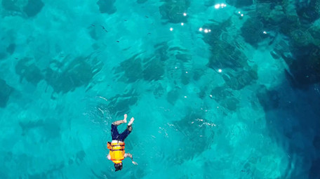 高空航拍在果冻色海洋里一个人浮潜寻找鱼