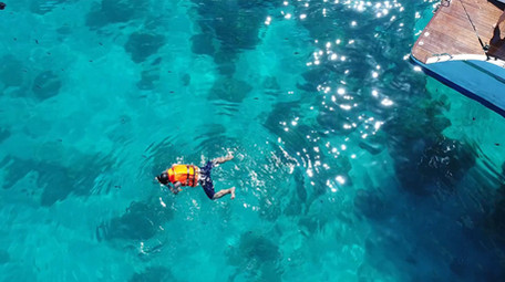 高空航拍在果冻色海洋里一个人浮潜寻找鱼