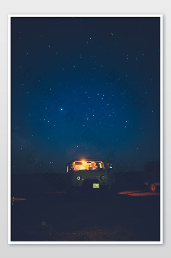 闪烁星空下亮着车灯的汽车图片