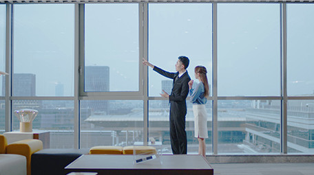 商务室内西装男女窗边指点实拍