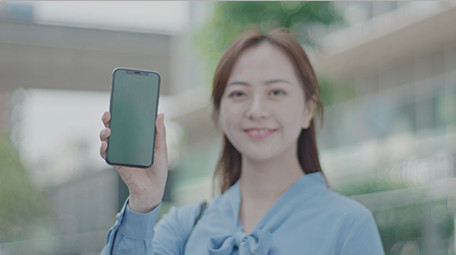 商务女微笑举起手机室外实拍近景