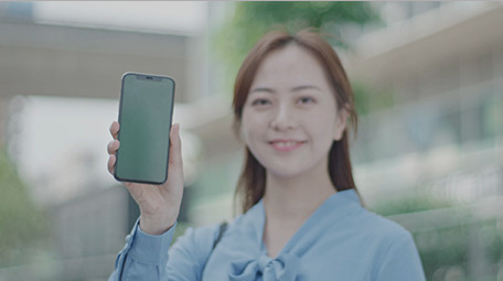 商务女微笑举起手机室外实拍近景