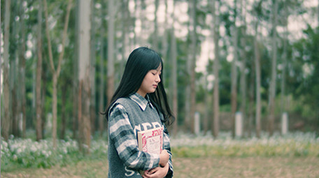 4K实拍女学生抱着书行走在唯美的森林