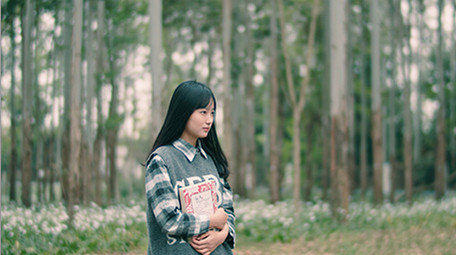 4K实拍女学生抱着书行走在唯美的森林