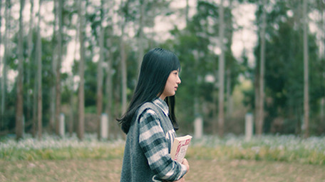 4K实拍女学生抱着书行走在唯美的森林