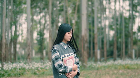 4K实拍女学生抱着书行走在唯美的森林