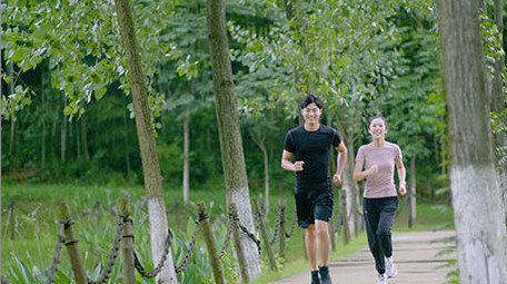 公园边跑步边交流的年轻情侣实拍