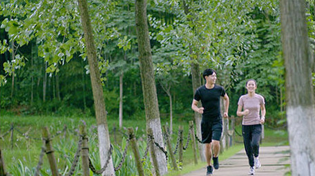 公园边跑步边交流的年轻情侣实拍