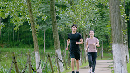 公园边跑步边交流的年轻情侣实拍