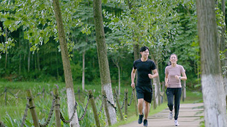 公园边跑步边交流的年轻情侣实拍